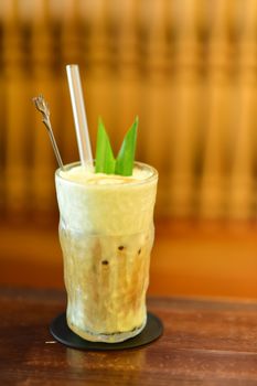 Chilled iced coffee topped with green tropical leaves in a frosty glass, perfect for a summer refreshment.
