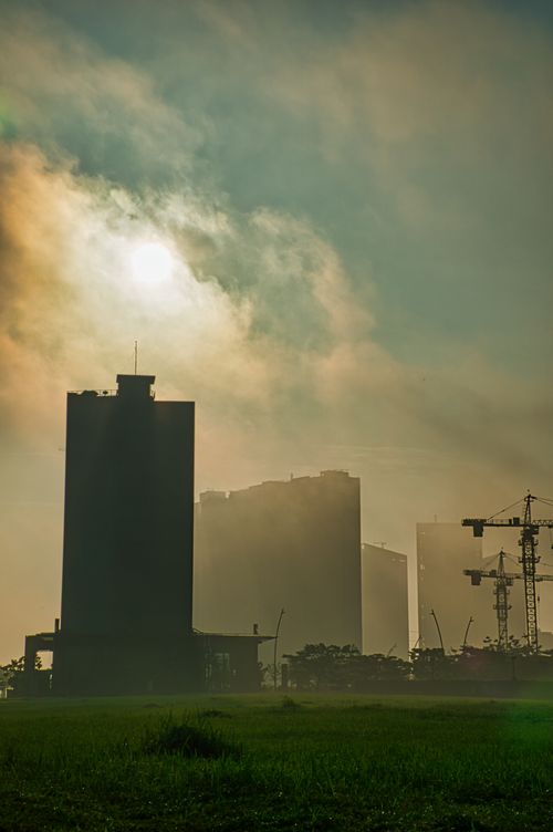 Free Skyscrapers and cranes silhouetted against a foggy sky in Banten, Indonesia at sunset. Stock Photo