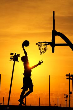 Dynamic silhouette of a basketball player dunking against a vivid sunset in Ilorin, Nigeria.