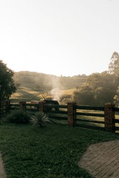 Tranquil rural scene with smoke rising, showcasing a peaceful countryside at dusk.
