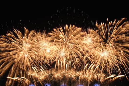 A breathtaking display of golden fireworks illuminating the night sky, creating a festive and celebratory atmosphere.