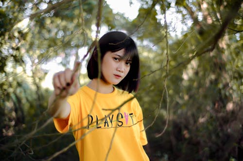 Free Woman in Yellow Crew Neck T-shirt Standing Under Green Tree Stock Photo