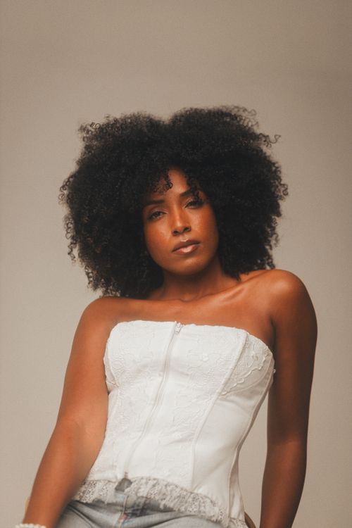 Free Elegant portrait of a woman with curly hair wearing a stylish white corset. Stock Photo
