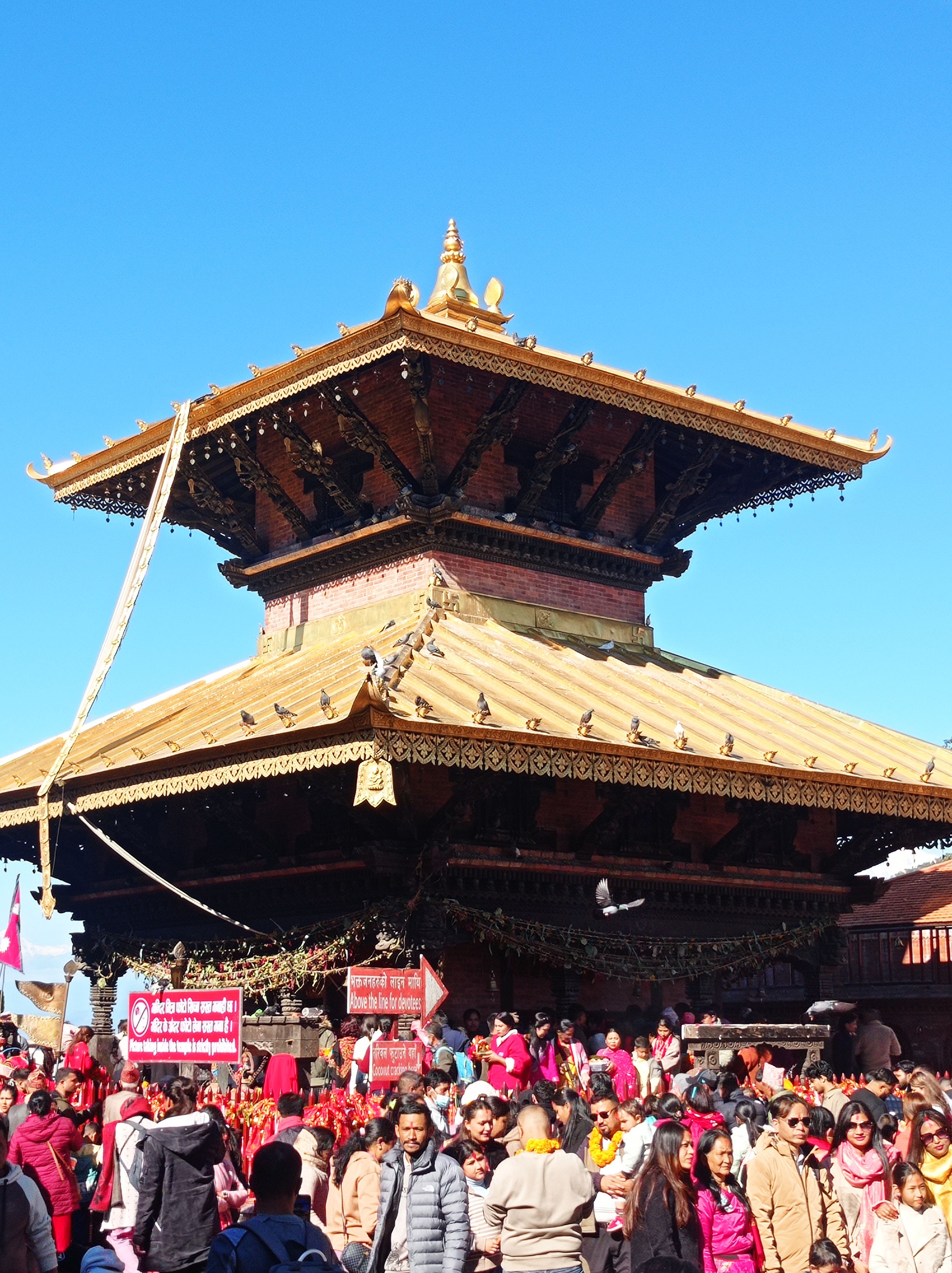 Crowd gathered at a traditional temple in Nepal with vibrant cultural attire and architecture.