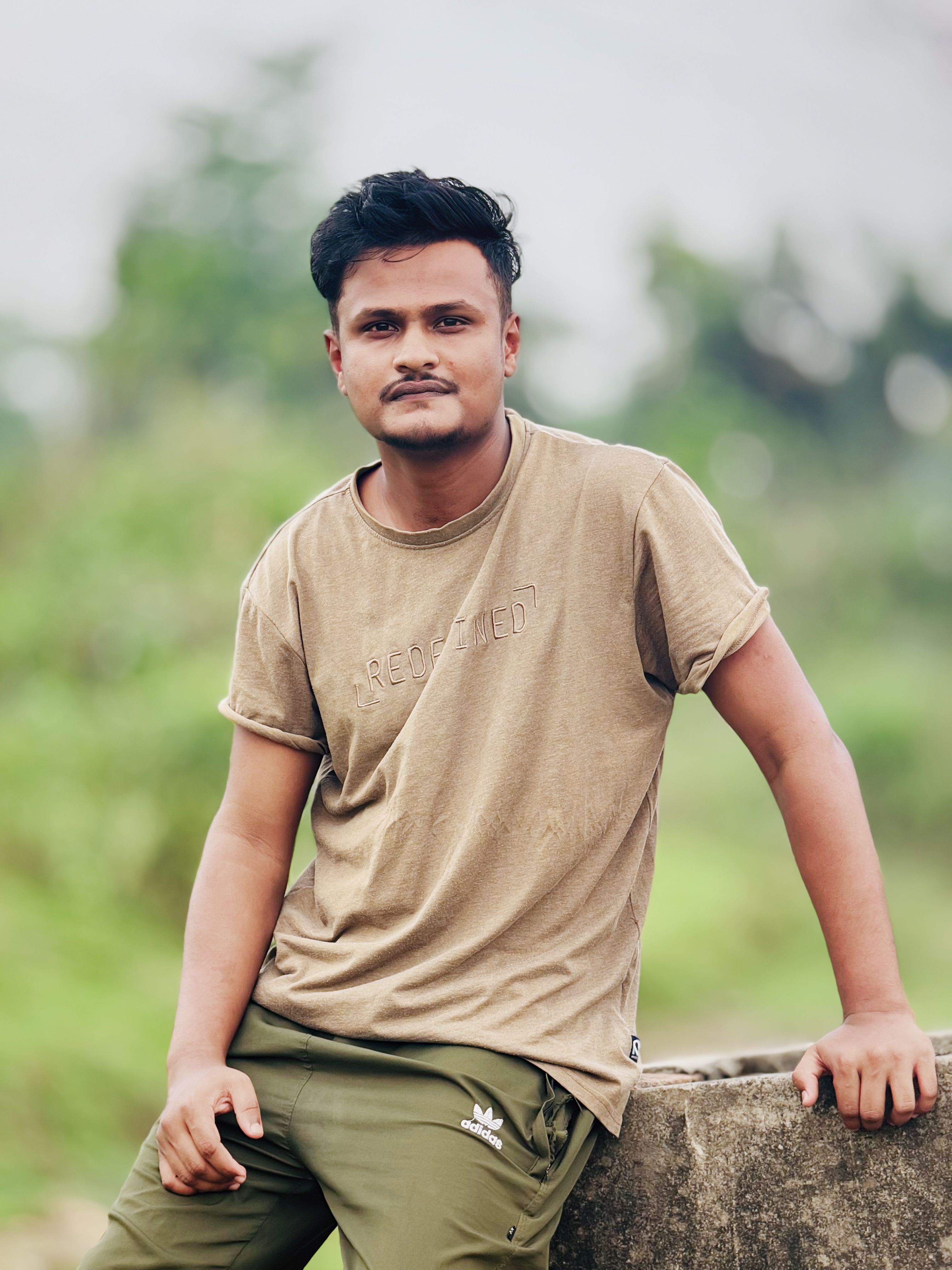 Portrait of a young man in casual attire posing outdoors, conveying a relaxed and confident demeanor.