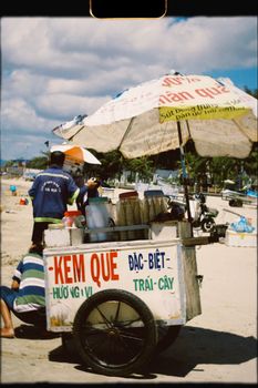 A vibrant ice cream cart on a sunny beach, offering refreshing treats to passersby.