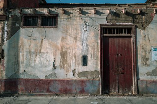 Free Weathered facade with red door and peeling paint in Trujillo, Peru, showing urban decay. Stock Photo