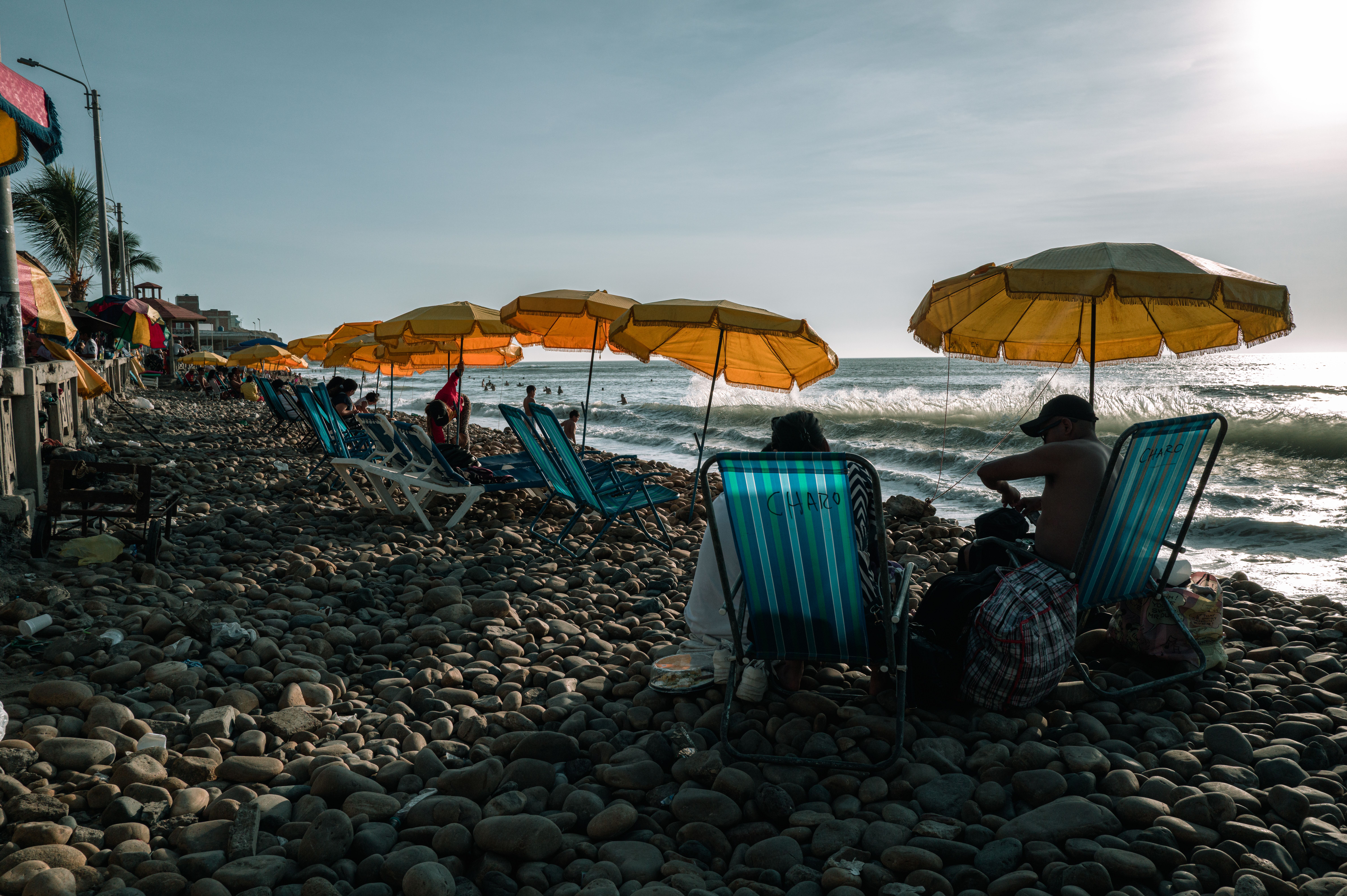 People enjoying the seashore under yellow umbrellas at Huanchaco Beach, Peru.