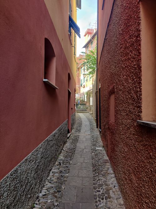 Free Colorful narrow alleyway in an Italian village with rustic architecture and cobblestone path. Stock Photo