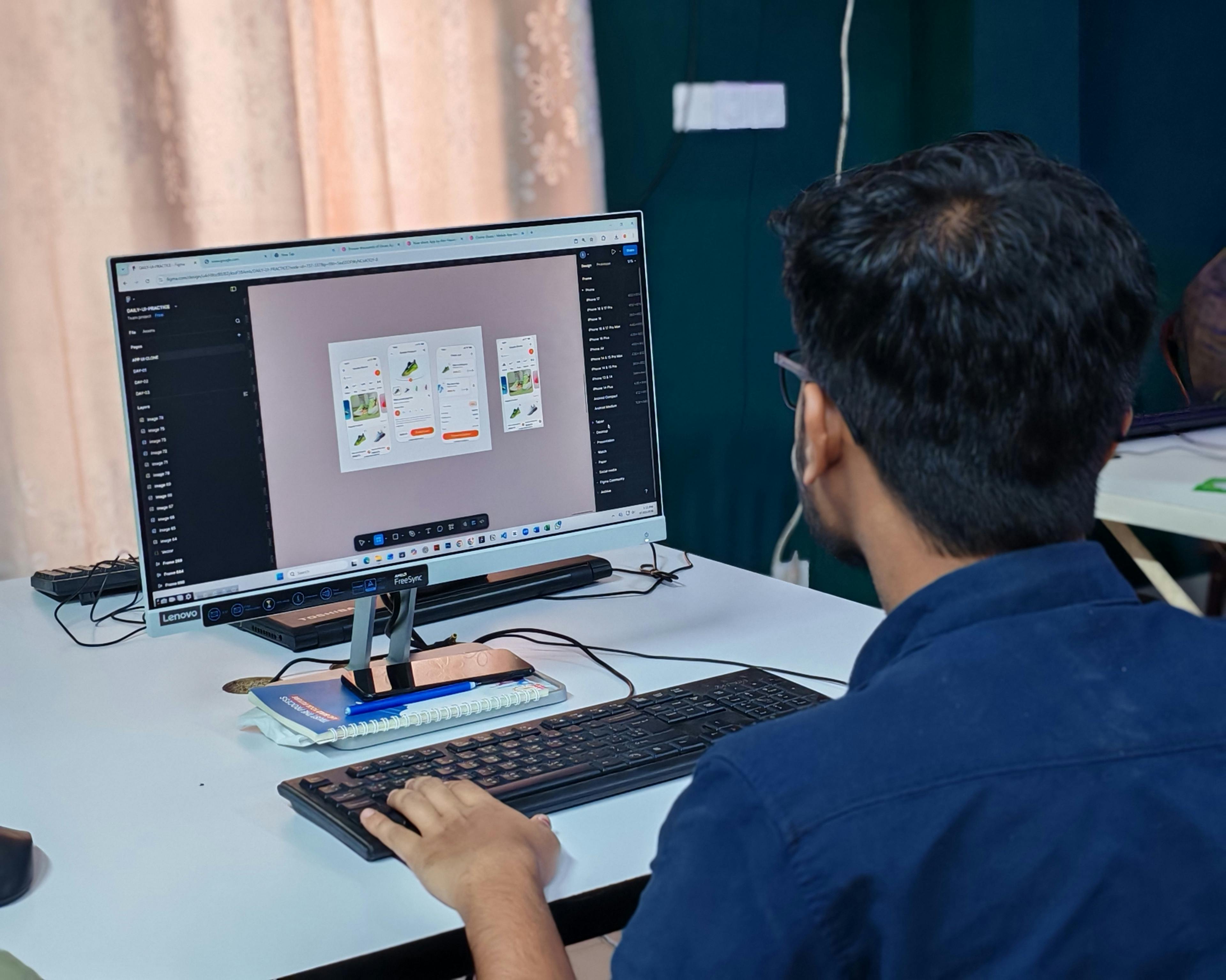 オフィス環境でデスクトップコンピュータのユーザーインターフェース作成に注力する若手デザイナー。
