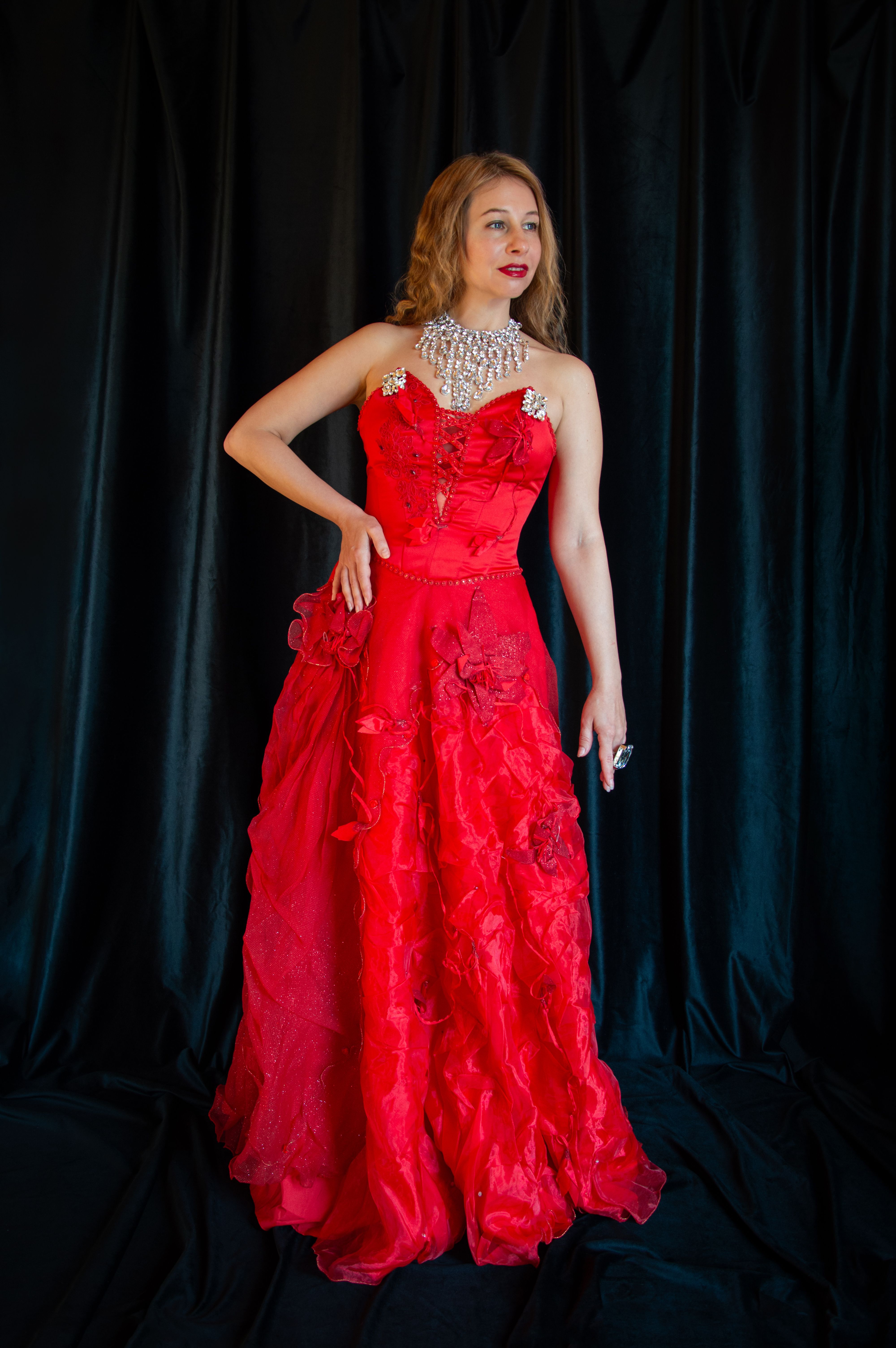 [ColoSach]-stunning-woman-in-a-red-evening-gown-and-jewel-necklace-posing-against-a-dark-backdrop.