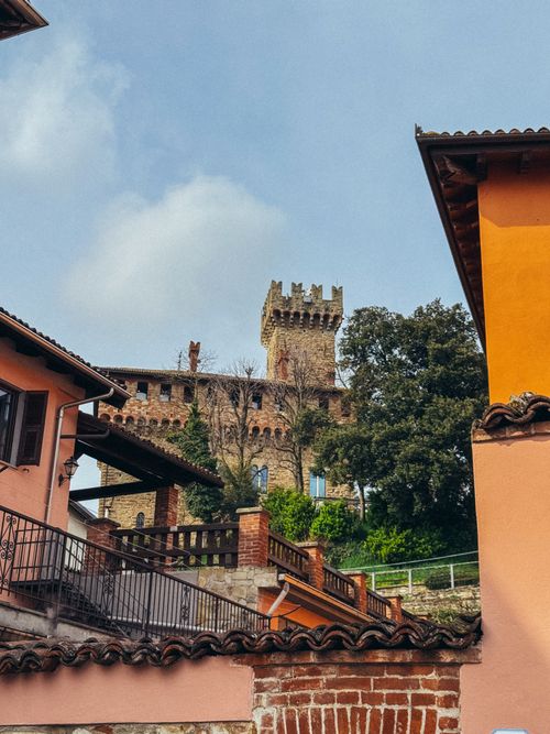 Free A beautiful medieval castle tower surrounded by colorful buildings in an Italian village. Stock Photo