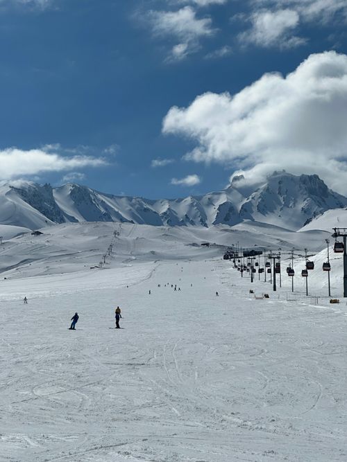 Free Picturesque snowy mountain landscape with skiers under a bright blue sky. Stock Photo
