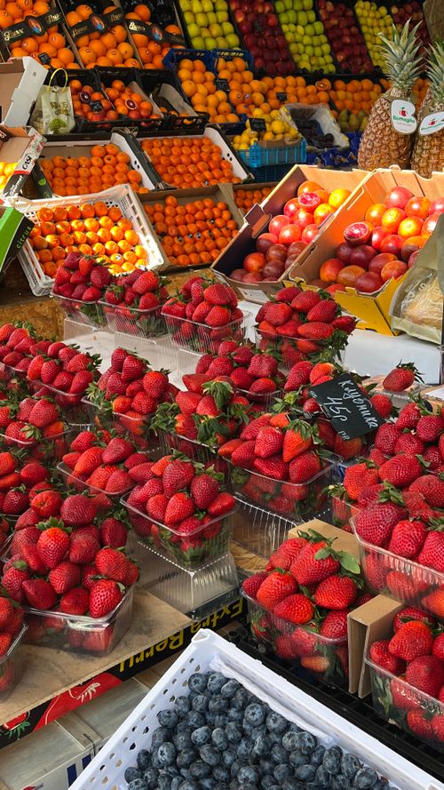 Free Colorful arrangement of fresh fruits including strawberries and blueberries at a bustling market stand. Stock Photo
