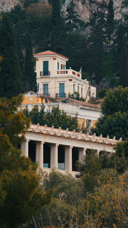Free Classic Greek buildings nestled among trees, showcasing traditional architectural style. Stock Photo