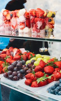 Vibrant display of fresh strawberries, grapes, and fruit cups in an outdoor setting.
