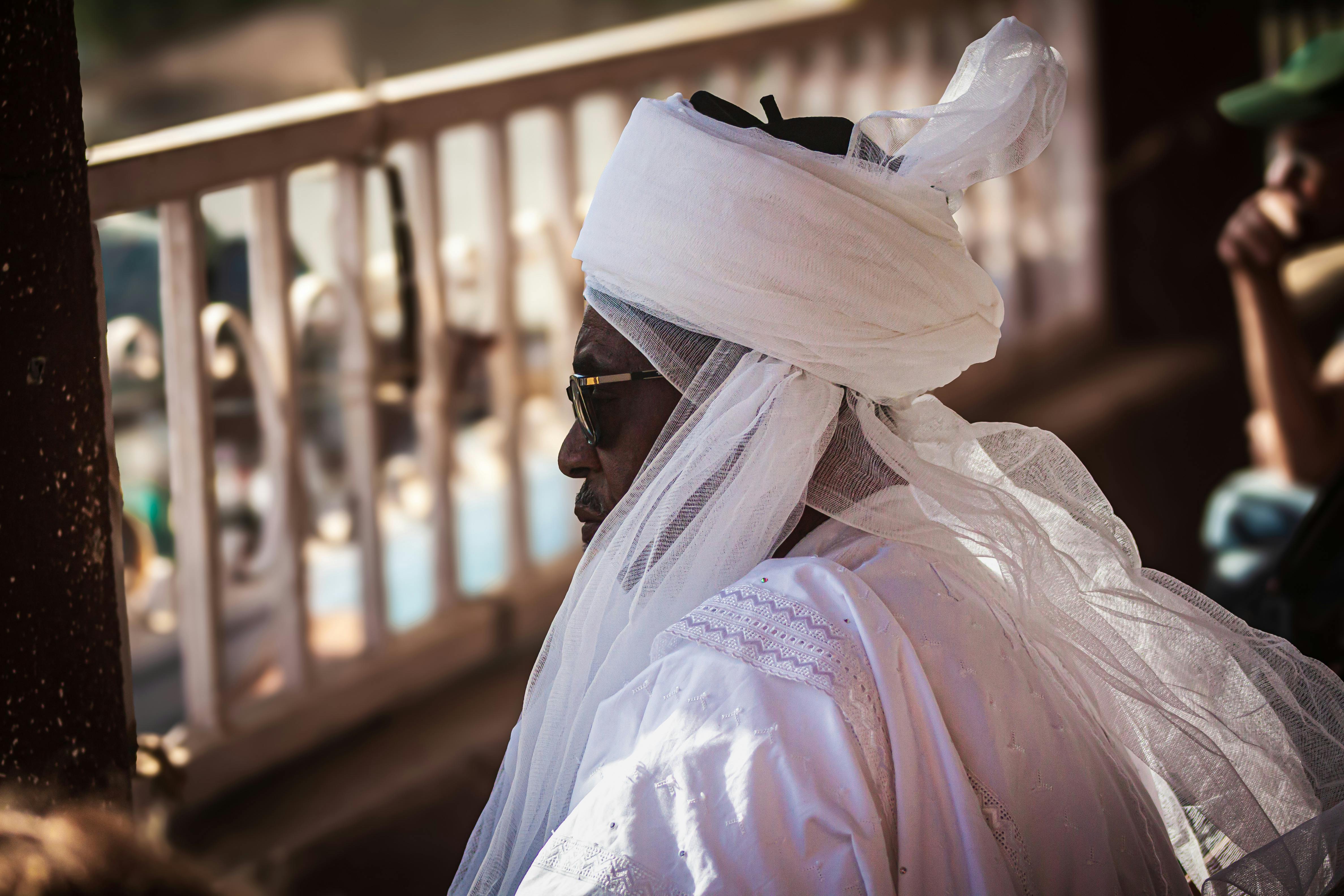 A portrait of an African elder in traditional attire, captured outdoors during the day.