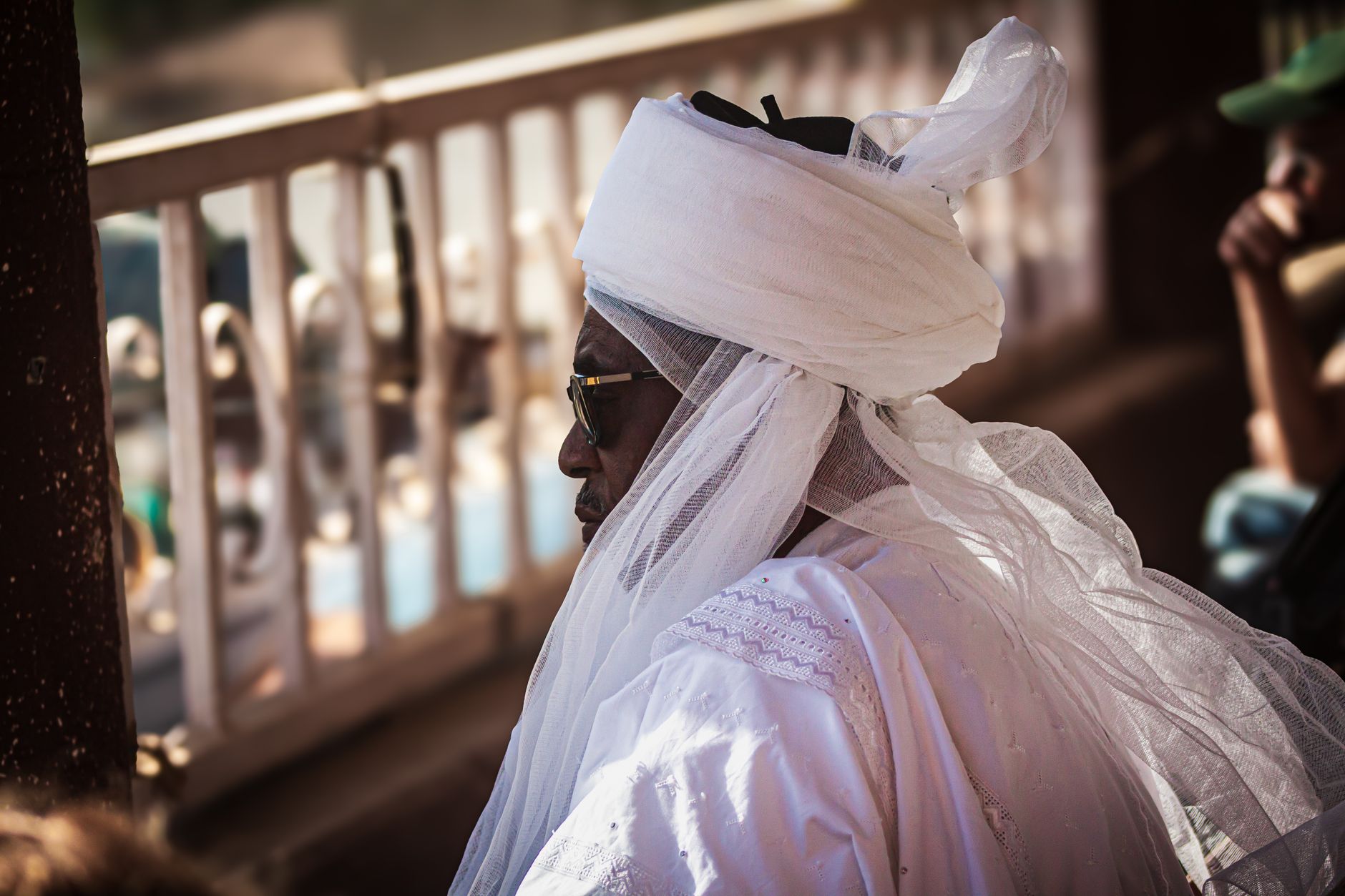 A portrait of an African elder in traditional attire, captured outdoors during the day.