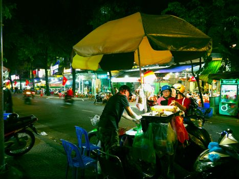 Nighttime street food market with bustling vendors and colorful lights.
