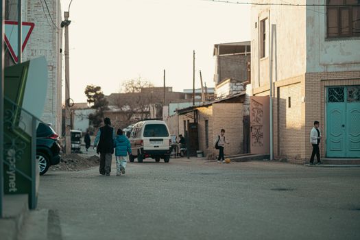 A quiet street in Bukhara, Uzbekistan at sunset, capturing daily life and local architecture.