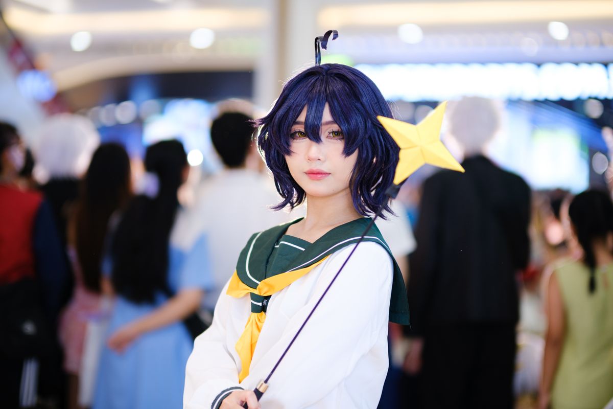 Cosplayer with star wand posing at a bustling indoor convention — first-con energy