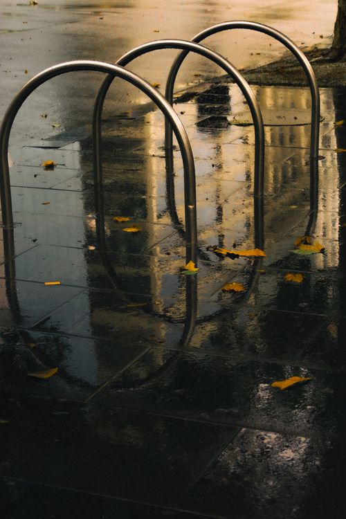 Free Rainy Melbourne street reflecting building and bike rack at dusk. Stock Photo