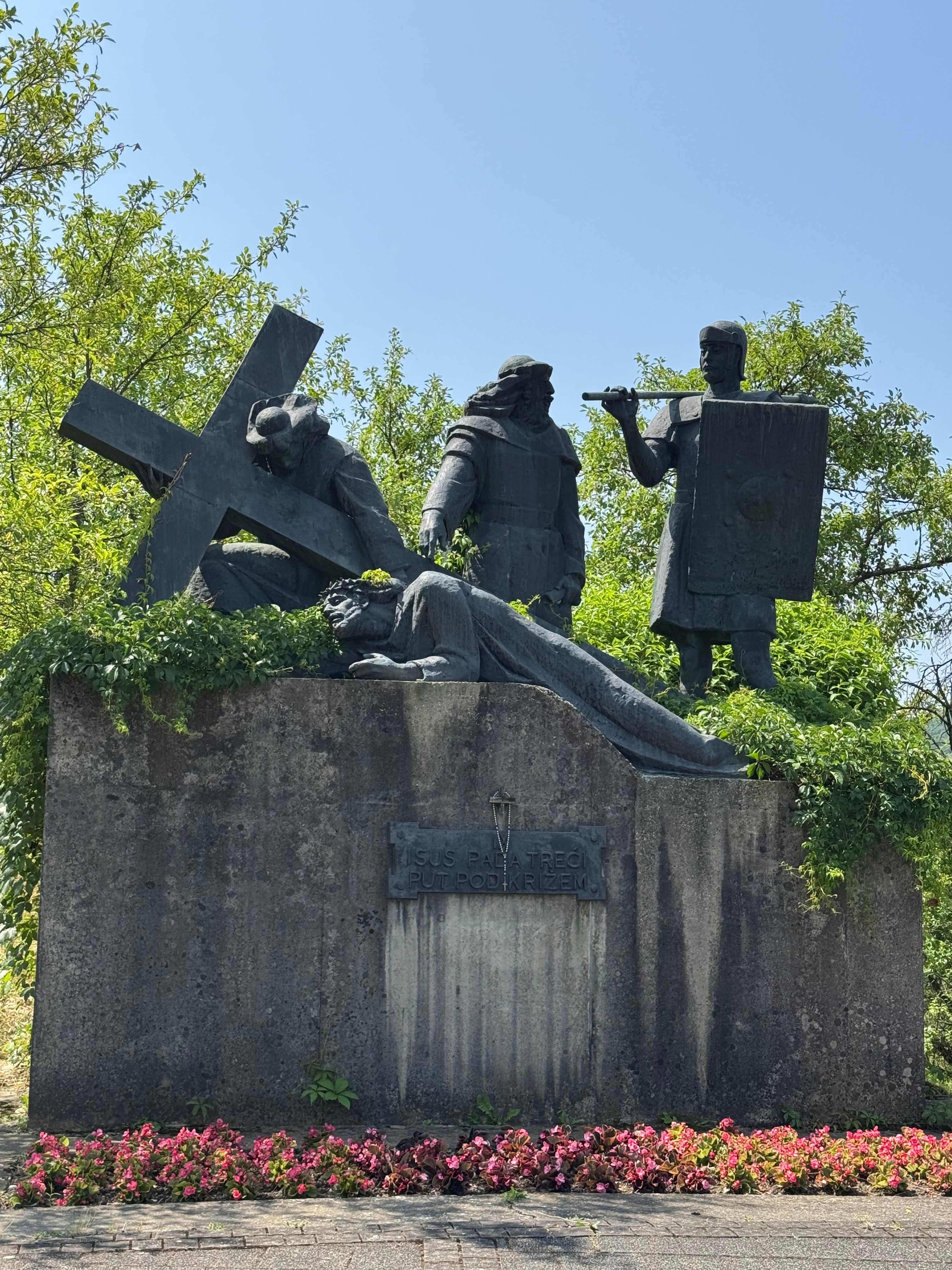 A dramatic sculpture scene of crucifixion in Marija Bistrica, Croatia, surrounded by lush greenery.