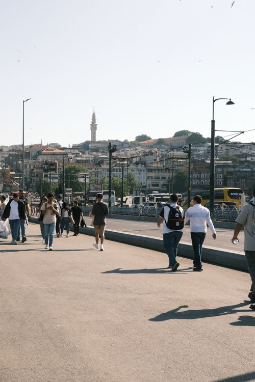Free People walk along a busy street with a city skyline and minaret background. Stock Photo