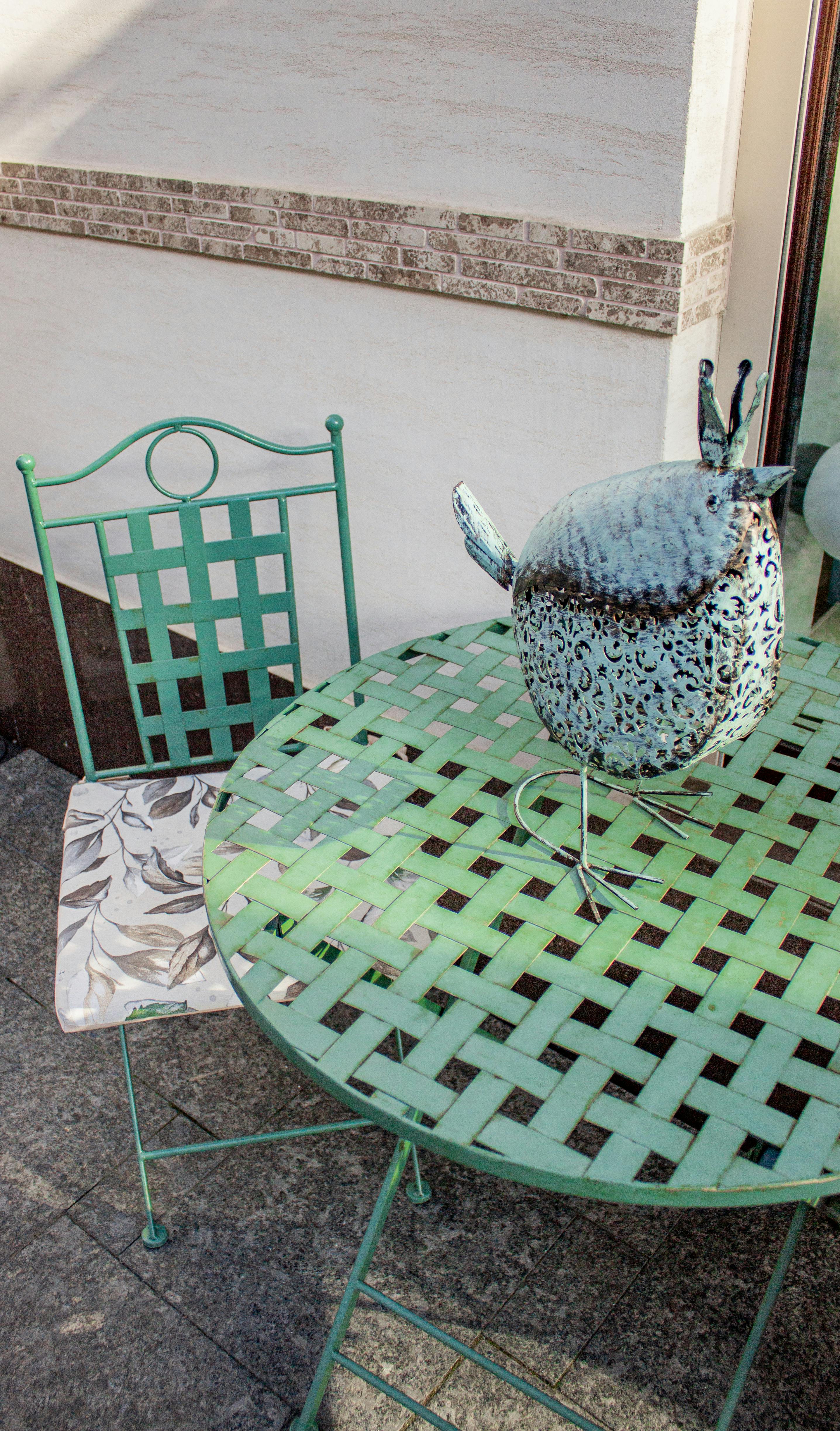 Green metal patio set with ornate bird sculpture, perfect for garden decor ideas.