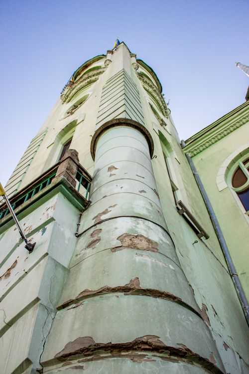 Free An upward perspective of a weathered green tower against a clear blue sky, showcasing architectural details. Stock Photo