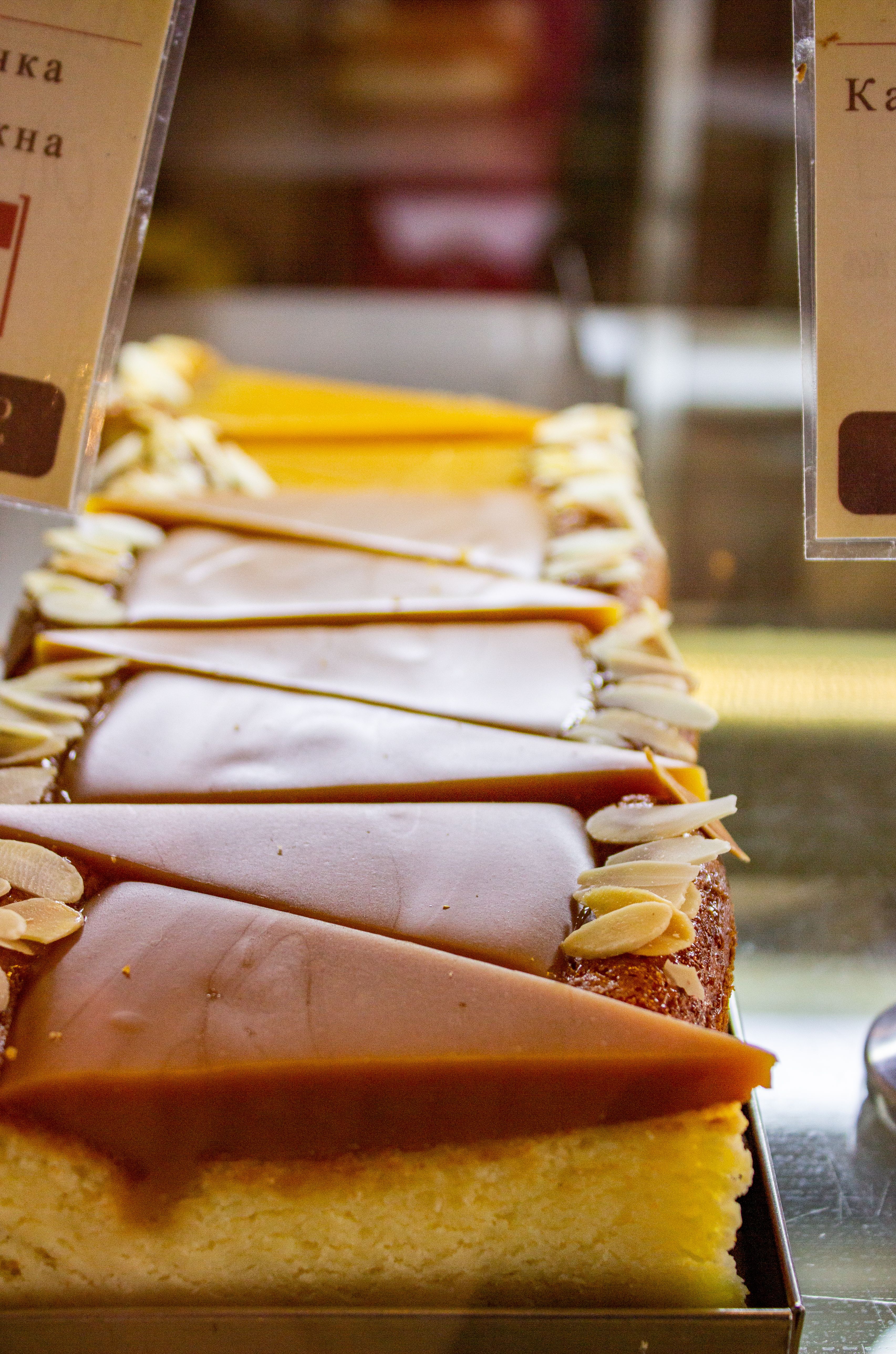 A mouth-watering view of caramel cheesecake slices with almond toppings in a bakery display.