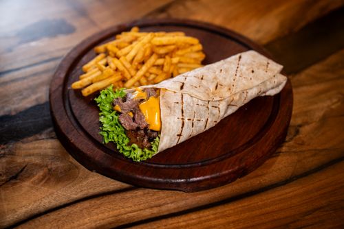 Free Delicious beef wrap with cheddar, lettuce and fries on wooden plate. Perfect for fast food lovers. Stock Photo