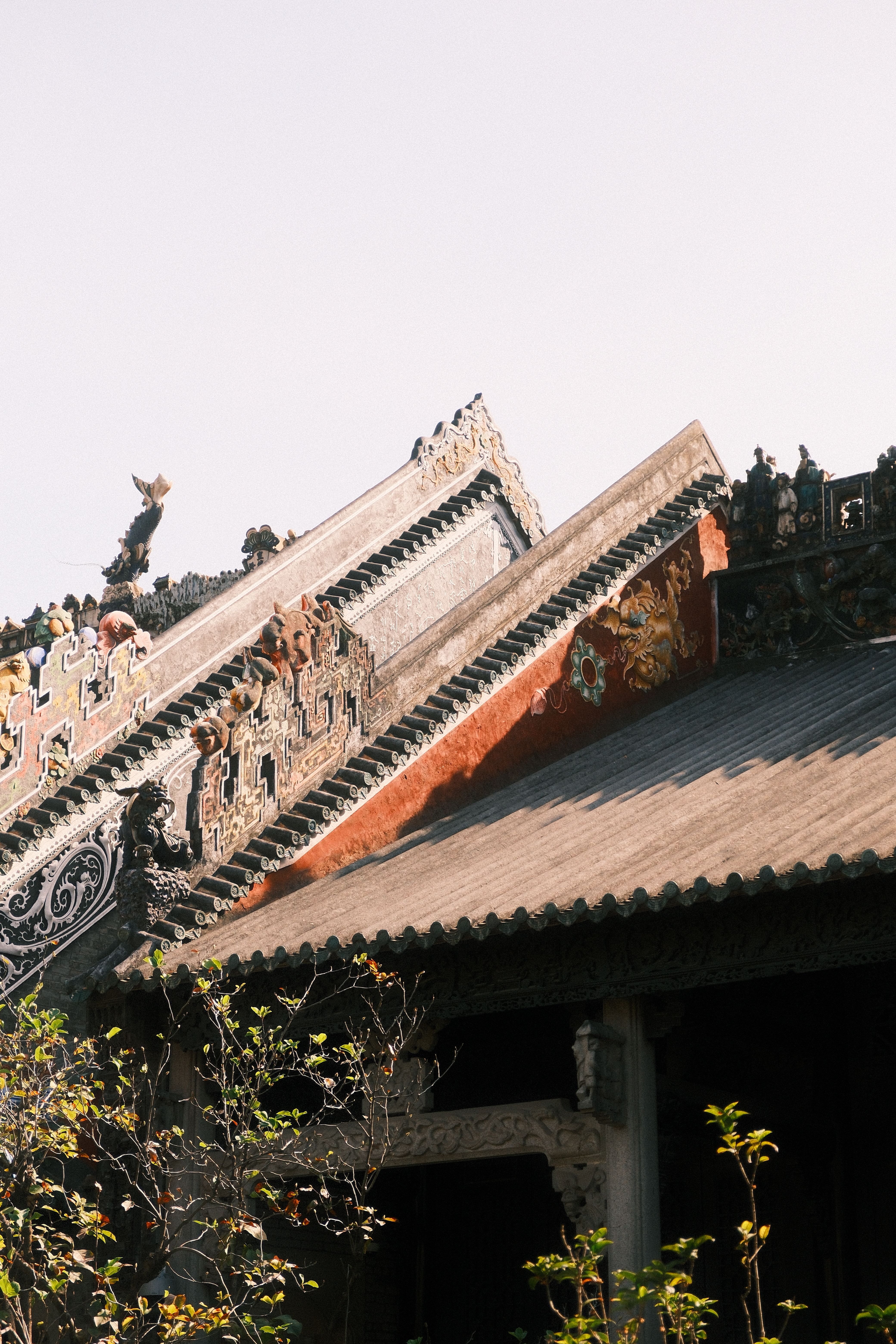 Traditional Chinese temple with intricate roof designs in Guangzhou, China, under clear skies.