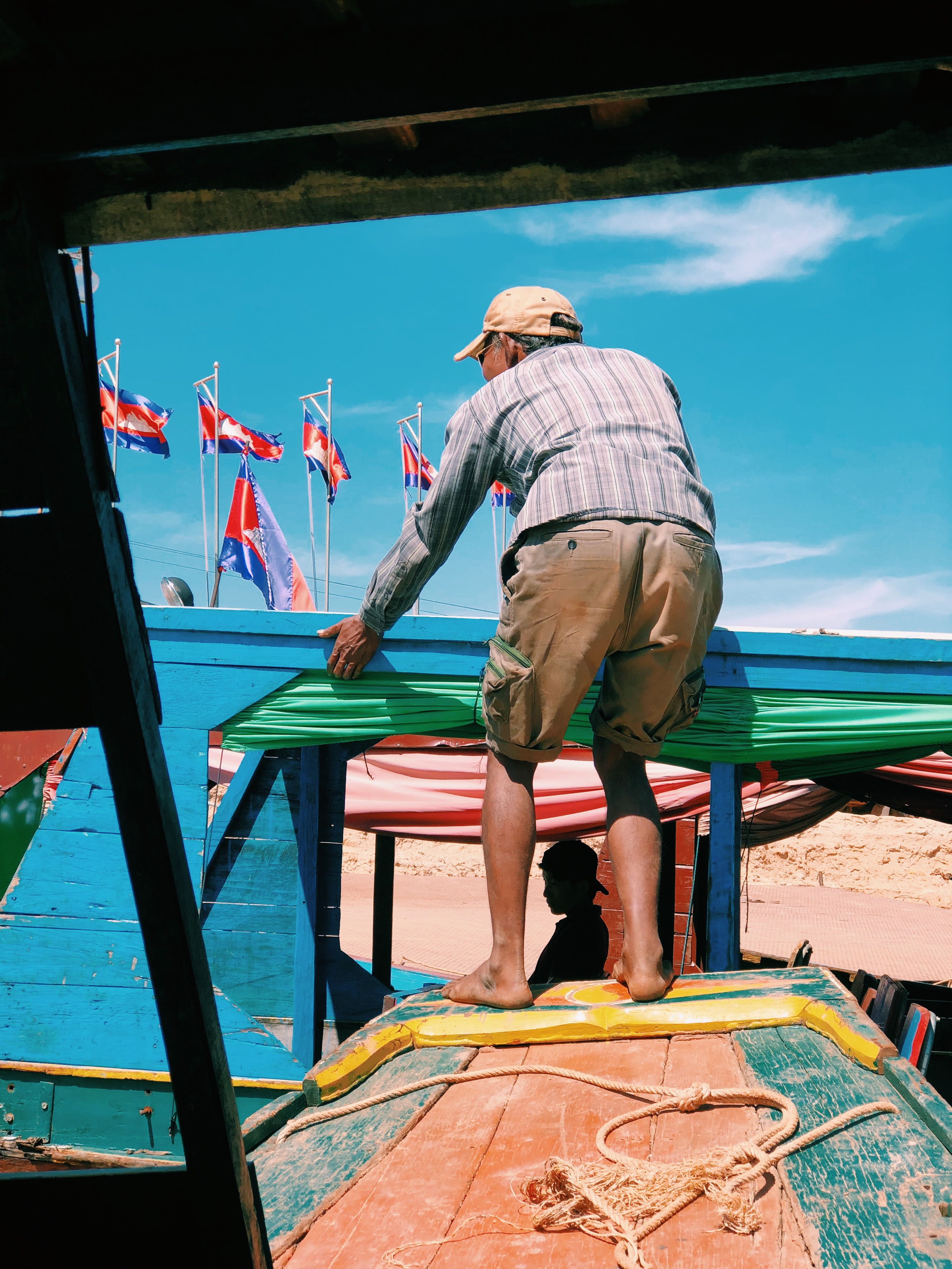 Man Balancing on Boat Deck in Vibrant Harbor · Free Stock Photo