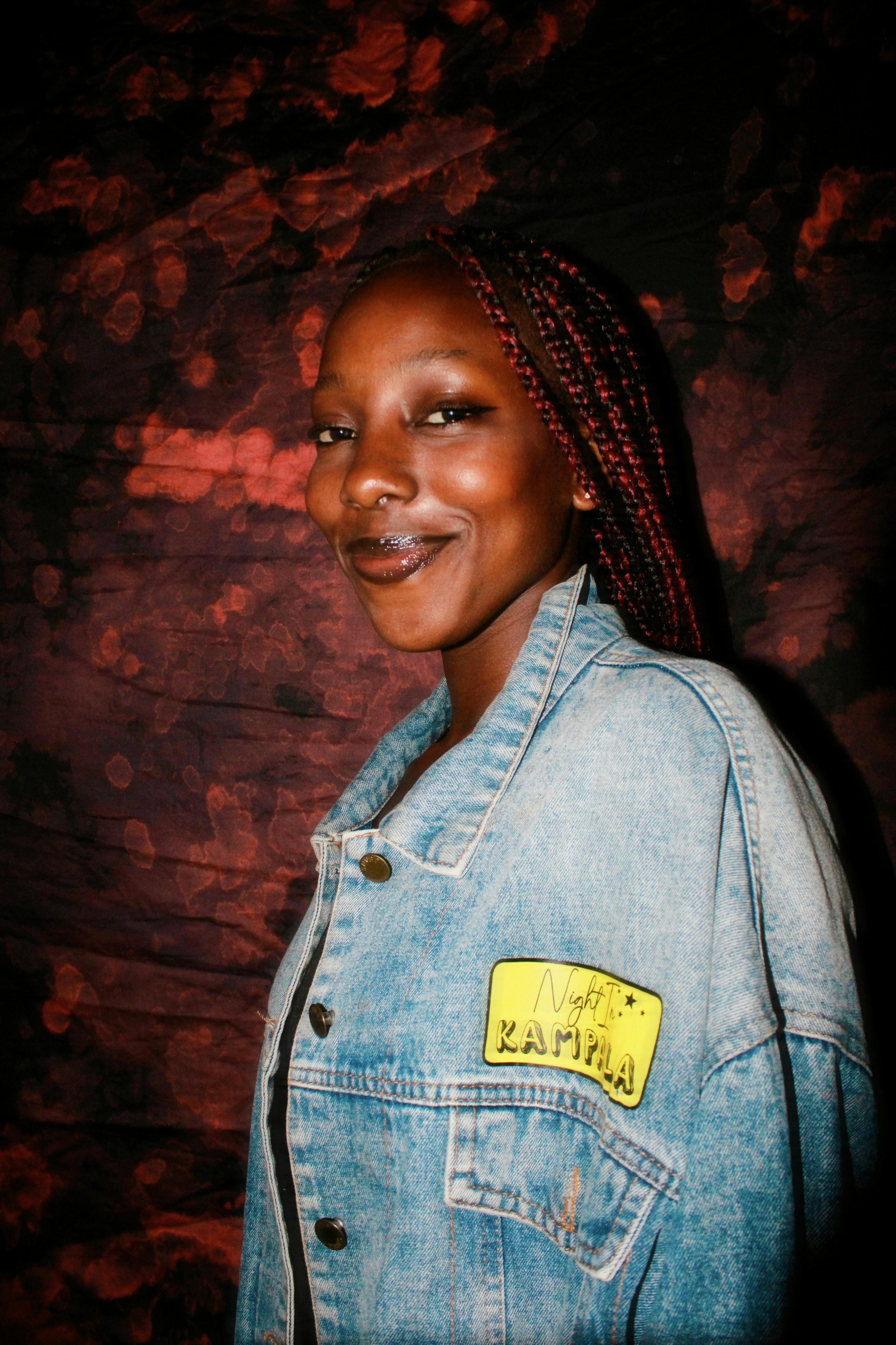 Portrait of a woman smiling confidently in a denim jacket with a vibrant artistic background.