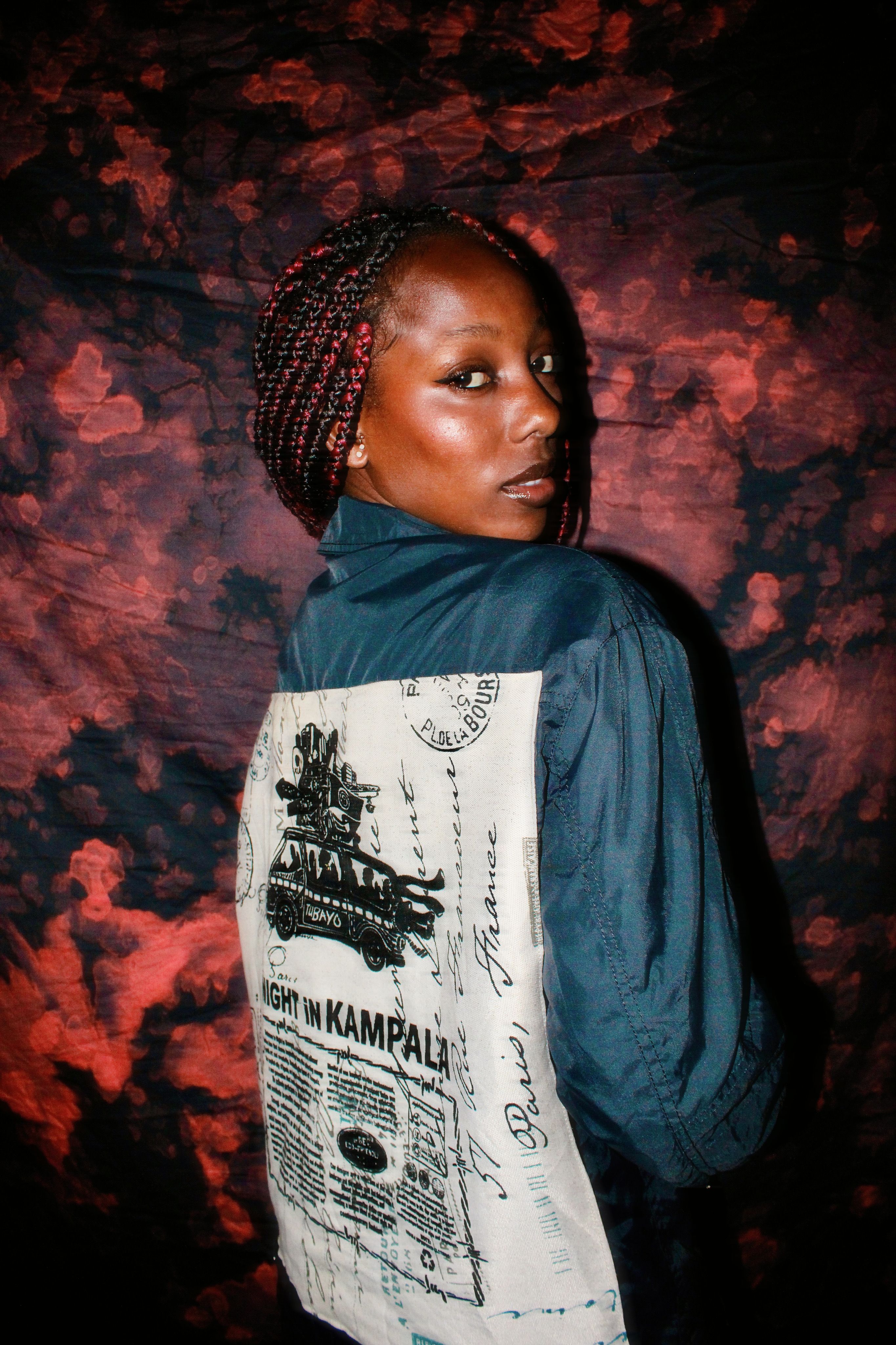 Stylish portrait of a woman showcasing vibrant fashion with braided hair and unique jacket.