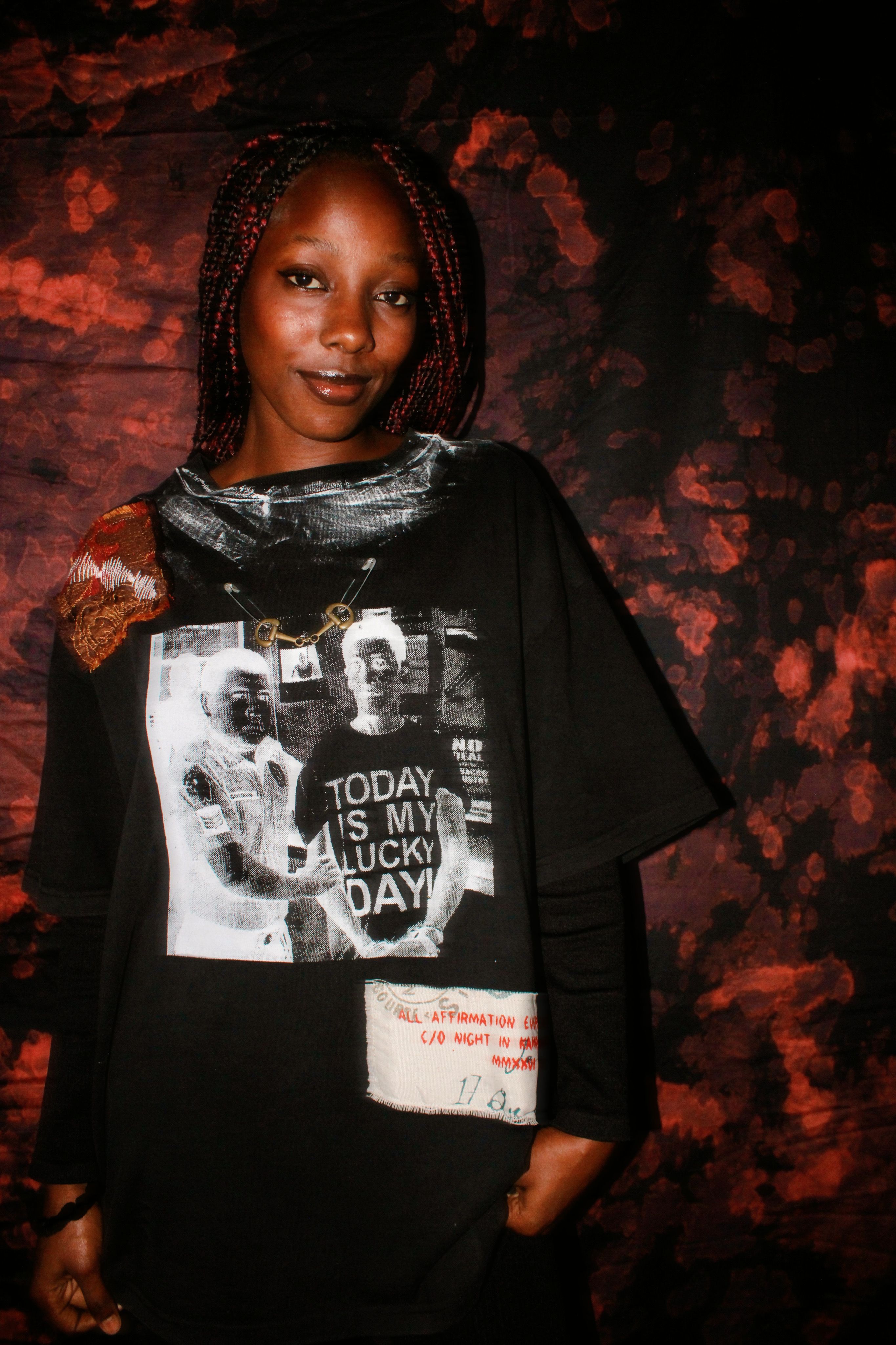 A fashionable woman in a graphic t-shirt poses confidently against a striking artistic background, exuding charm and style.