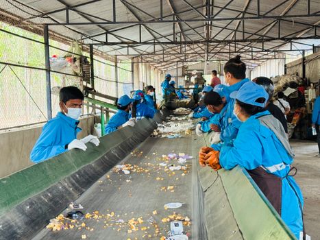 Workers in blue uniforms sorting waste at a recycling facility in Butwal, Nepal.
