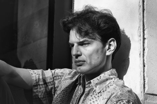 Free A thoughtful man in black and white, deep in contemplation against a sunlit wall. Stock Photo
