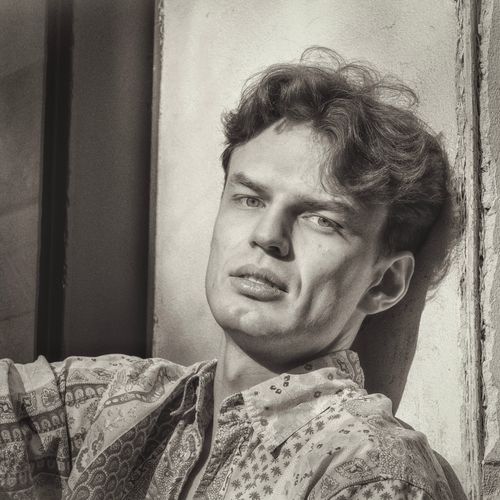 Free A striking black and white portrait of a man leaning against a wall in Berlin, capturing thoughtful emotion. Stock Photo