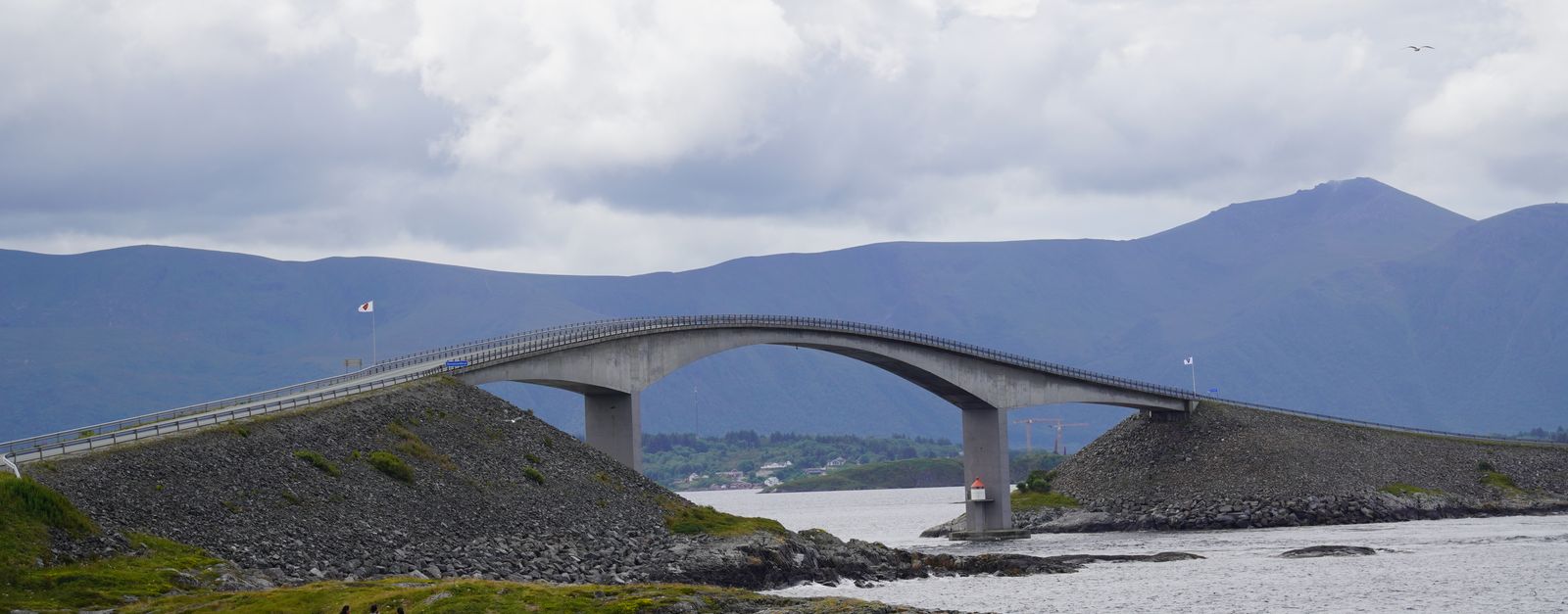 Scenic view of the iconic Storseisundet Bridge on the Atlantic Ocean Road in Norway, surrounded by picturesque mountains.