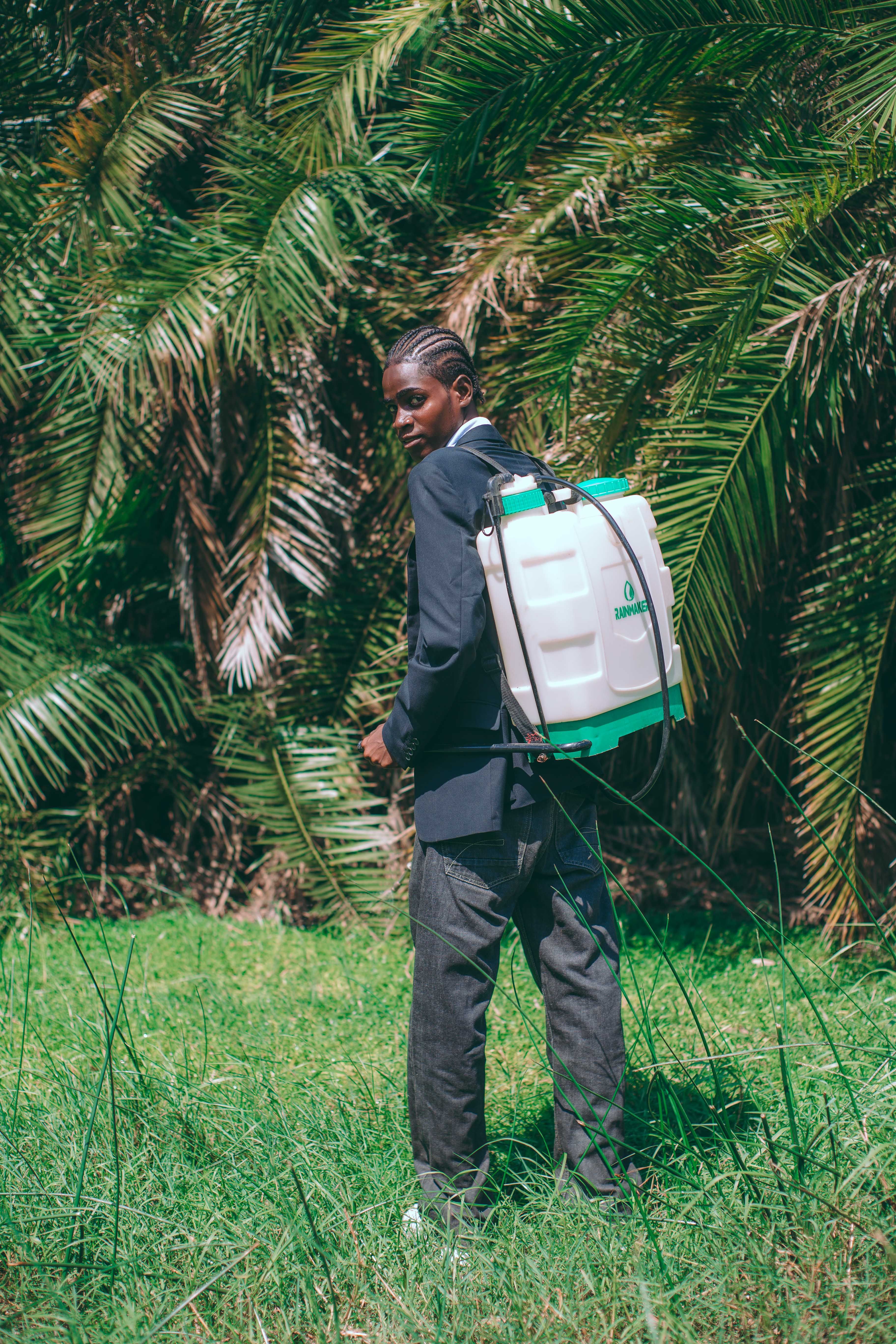 African agrochemical spraying worker with backpack sprayer