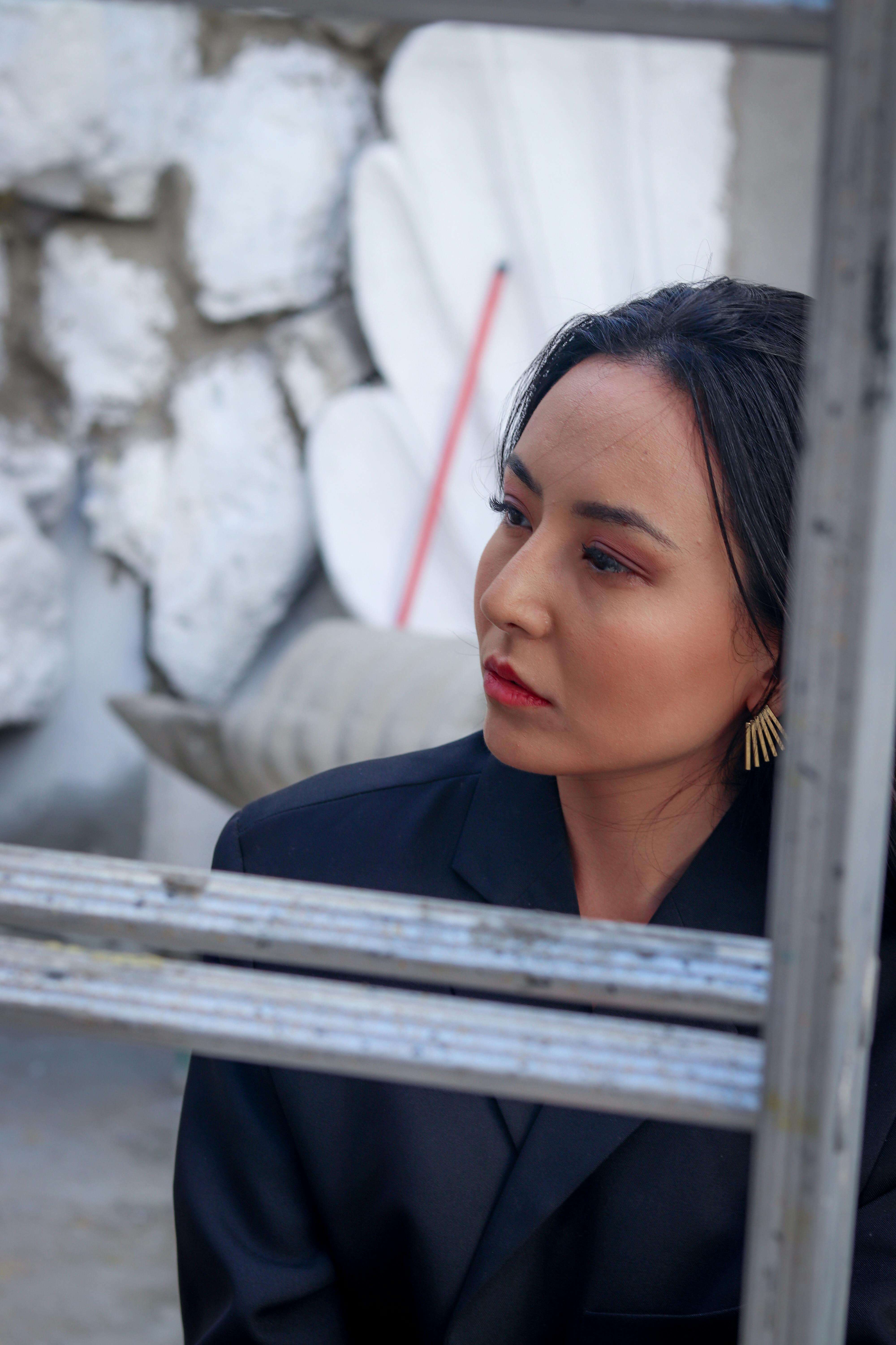 Stylish woman outdoors in black blazer, expressing a contemplative mood.