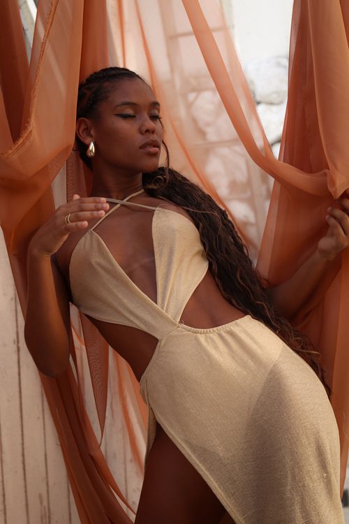 Free A fashionable woman poses gracefully in a golden dress surrounded by flowing fabric, exuding elegance and style. Stock Photo