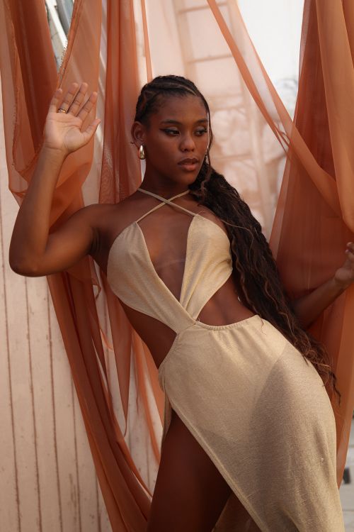 Free A fashionable portrait of a woman posing in a beige dress with flowing fabric, exuding elegance and style. Stock Photo