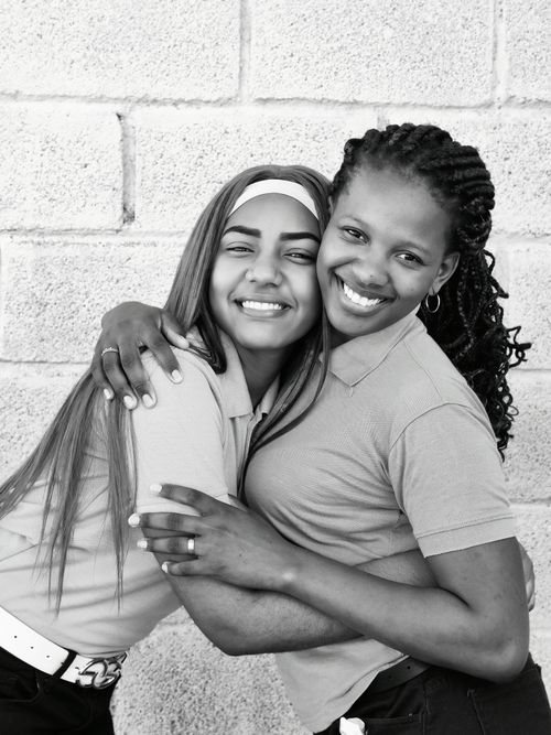 Free A heartwarming black and white portrait of two young women embracing, showcasing friendship and happiness. Stock Photo