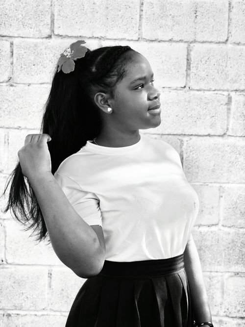 Free Black and white portrait of a young woman against a brick wall, exuding confidence. Stock Photo
