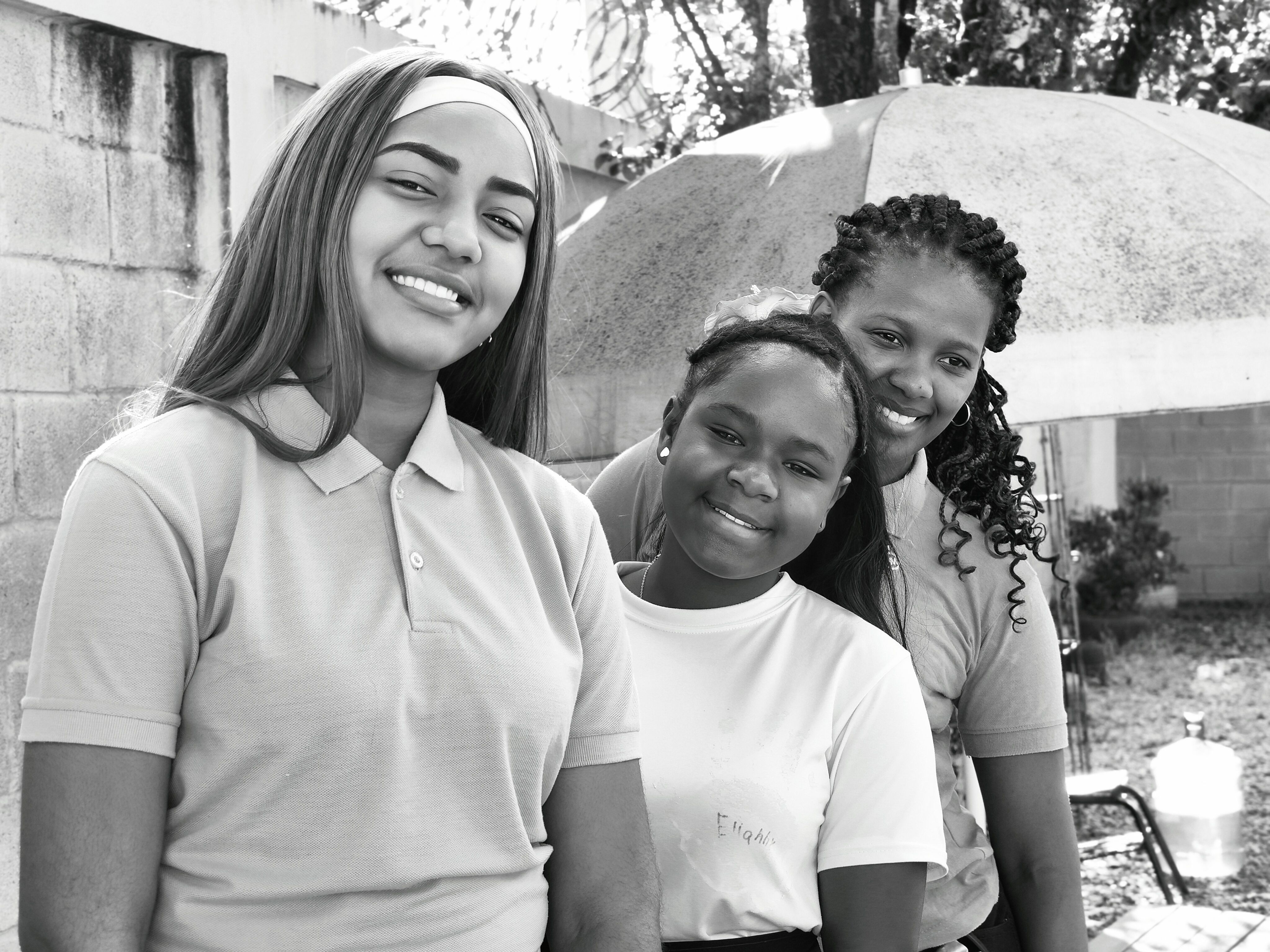 Three Young Women Smiling Outdoors in Black and White · Free Stock Photo