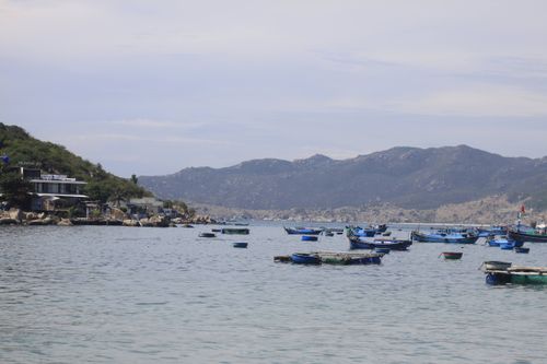 Free Scenic view of a coastal fishing village with traditional boats against a mountainous backdrop. Stock Photo