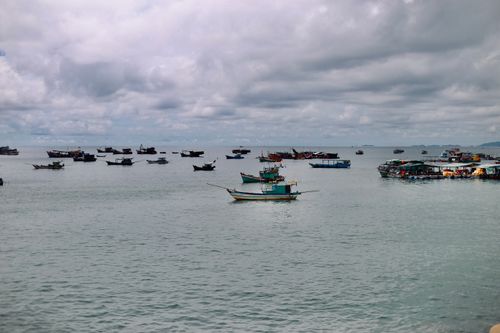 Free A scenic view of multiple fishing boats on a cloudy day at sea, creating a serene atmosphere. Stock Photo